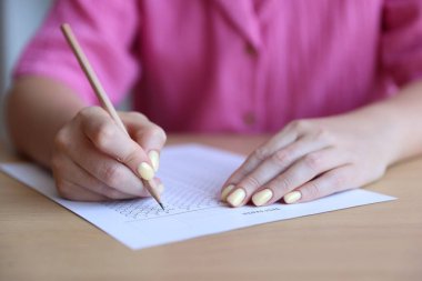 Tahta masada çoklu seçim testi dolduran öğrenci, yakın çekim. Sınavı geçmek