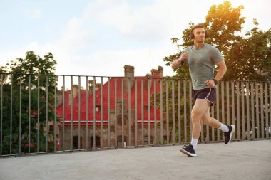 Spor giyimli atletik genç adam dışarıda koşuyor, mesaj için yer var.