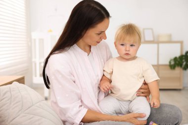 Anne, küçük sevimli bebeğiyle odada yatıyor.