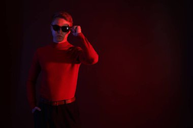 Güneş gözlüğü takan yakışıklı bir adam karanlık arka plana karşı neon ışıklar takıyor. Metin için boşluk