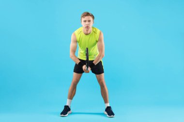 Açık mavi arka planda tenis raketi olan bir adam.