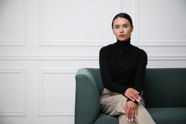 Beyaz duvarın yanındaki kanepede güzel bir kadın. Metin için boşluk