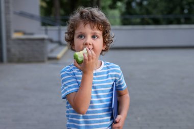 Dışarıda elma yiyen şirin bir çocuk. Okul yemeği.