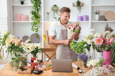 Profesyonel çiçekçi dükkandaki ahşap masada çiçek buketi yapıyor.