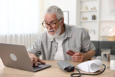 Hapları olan kıdemli bir adam içeride bilgisayarla doktorla görüşüyor.