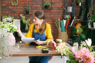 Dükkandaki ahşap masada çalışan profesyonel bir çiçekçi.