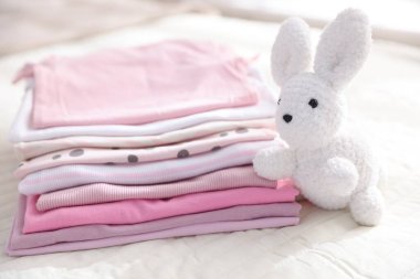 Temiz bebek kıyafetleri ve çarşaflara aksesuar yığını.