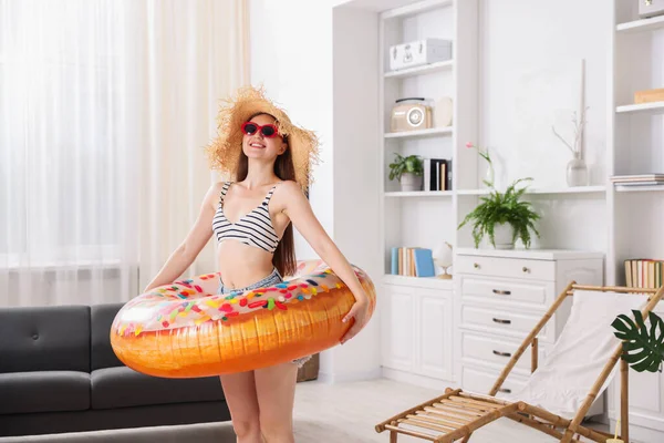 Güneş gözlüklü, hasır şapkalı, şişme yüzüklü mutlu kadın evde eğleniyor. Denizde tatilin hayalini kuruyorum.