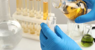 Bilim adamı beyaz masada su örneklerini test ediyor, yakın plan.