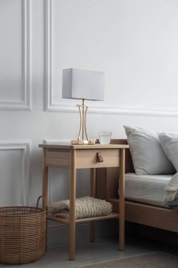 Yatak odasının yanında lamba ve bir bardak su olan komodinin yanında.