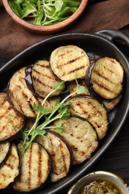 Tahta masada servis edilen mikroyeşillikli ızgara patlıcan dilimleri.