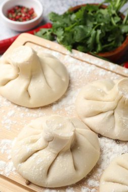 Pişmemiş khinkaliler (hamur tatlısı), biberler ve maydanozlar masada, yakın plan.