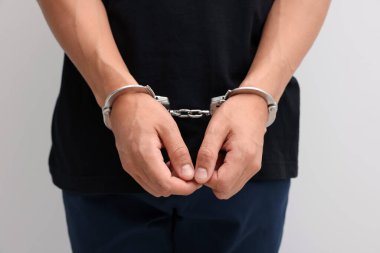 Hafif arka planda metal kelepçeli adam, yakın plan.