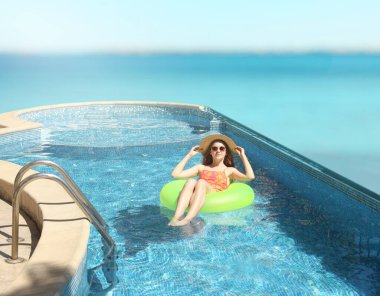 Yüzme havuzunda yüzen şişme yüzüklü bir kız.