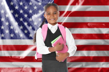 ABD bayrağına karşı sırt çantası ve defterleri olan küçük bir kız. Dil okulu