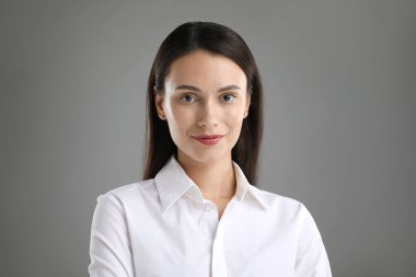 Gri arka planda kendine güvenen bir iş kadınının portresi