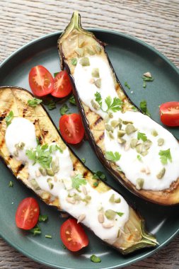 Kabak çekirdekli ızgara patlıcan, domates ve yoğurt dilimleri, ahşap masa, üst manzara.