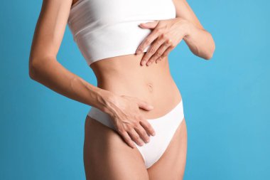 Açık mavi arka planda düz göbekli kadın, yakın plan.