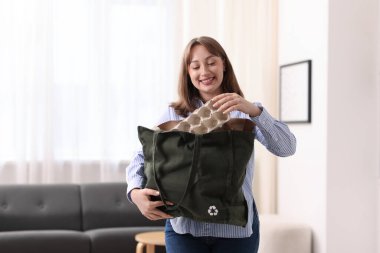 Geri dönüşüm. Elinde bir çanta dolusu farklı atık kağıtla gülümseyen kadın.