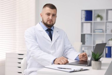 Klinikte dizüstü bilgisayarla çalışan bir doktor. Online tıbbi danışmanlık