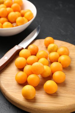 Olgun sarı kiraz erikleri, ahşap tahta ve bıçak siyah masada, yakın plan.