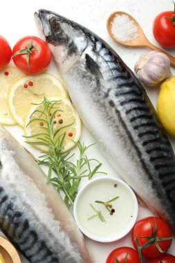 Taze çiğ uskumrular ve baharatlar beyaz masada, düz yerde. Deniz ürünleri lezzetleri.