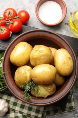 Lezzetli, dereotlu haşlanmış patates, kasede yağ, gri desenli masada tuz ve ürünler, düz uzanma.