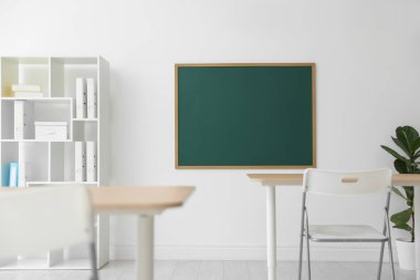 Boş yeşil karatahta, masalar, sandalyeler, raf ünitesi ve bitki sınıfı