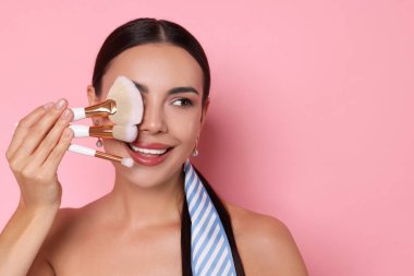 Pembe arka planda makyaj fırçası olan güzel bir kadın, mesaj için yer