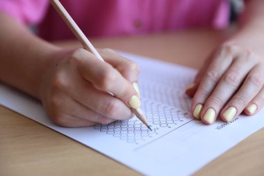 Tahta masada çoklu seçim testi dolduran öğrenci, yakın çekim. Sınavı geçmek