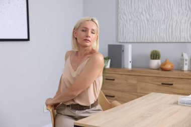 Ofiste sandalyeye uzanan olgun bir kadın.