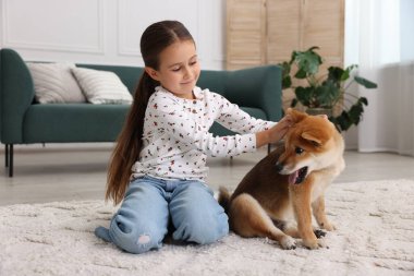 Evde köpeğiyle yerde yatan sevimli küçük bir kız. Çocuk ve hayvan