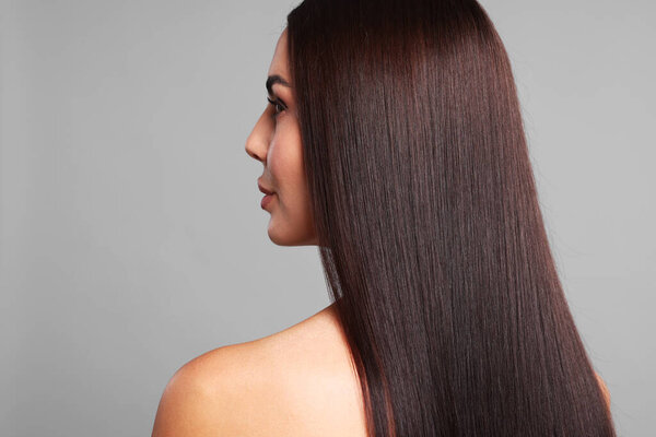 Woman with beautiful smooth hair after lamination procedure on light grey background, back view. Space for text