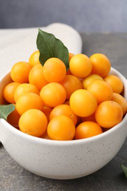 Olgun sarı kiraz erikleri ve yaprakları Gri masada, yakın plan