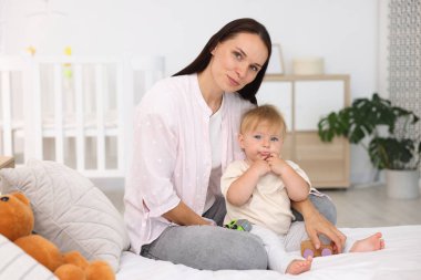 Anne ve tatlı bebeği yatakta oyuncaklarla oynuyorlar.