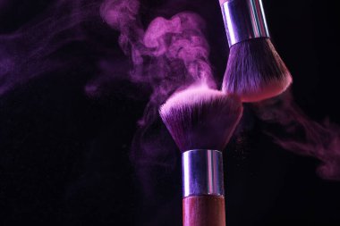 Siyah arka planda mor göz farlı makyaj fırçaları, yakın plan. Metin için boşluk