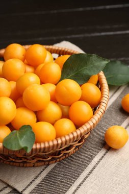 Olgun sarı kiraz erikleri ve koyu ahşap masada yapraklar, yakın plan.