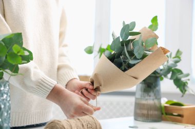 Çiçekçi çiçekçide okaliptüs dallarından güzel bir buket yapıyor, yakın plan.