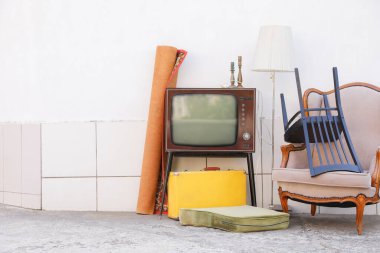 Tribünde Retro TV, koltuk ve beyaz duvarın yanında kullanılan diğer şeyler. Metin için boşluk