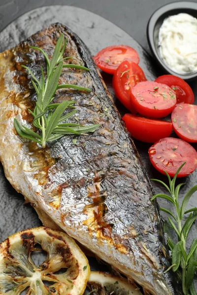 Siyah masanın üstünde baharat ve sosla servis edilen lezzetli kızarmış uskumrular. Ev yapımı deniz ürünleri yemeği.