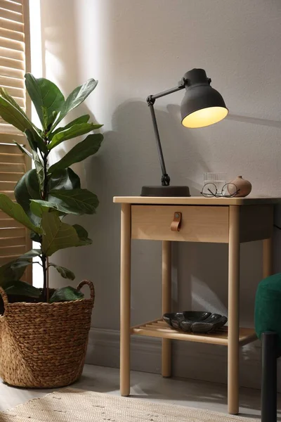 Bir bardak su, lamba ve bardaklı ahşap masa.