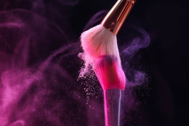 Renkli göz gölgeli makyaj fırçaları siyah arka planda neon ışıkları, yakın plan