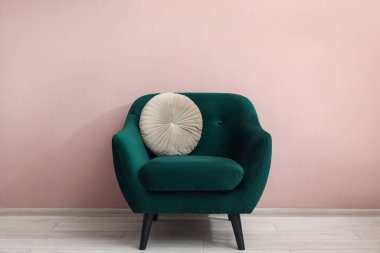 İçerideki bej duvarın yanında rahat koltuk ve yastık.