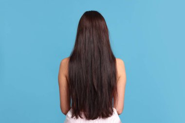 Açık mavi arka planda saçı zarar görmüş bir kadın.