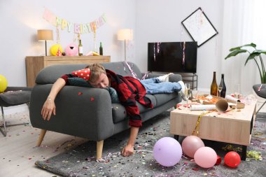 Adam partiden sonra dağınık bir odada kanepede akşamdan kalma.