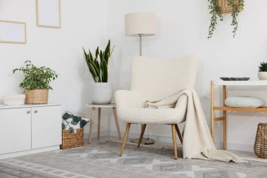 Şık koltuk, lamba, dolap, konsol masası ve oda çiçekleri. İç tasarım