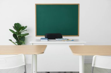Boş yeşil karatahta, masalar, sandalyeler ve bitkiler sınıfta