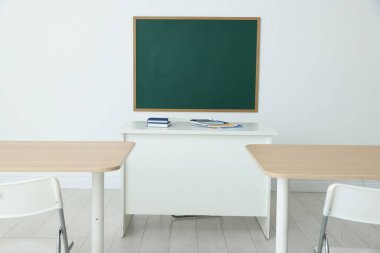 Boş yeşil karatahta, sınıfta masalar ve sandalyeler