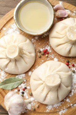 Biber, un ve defne yapraklarıyla ahşap masa üzerinde pişmemiş khinkaliler (hamur tatlısı)