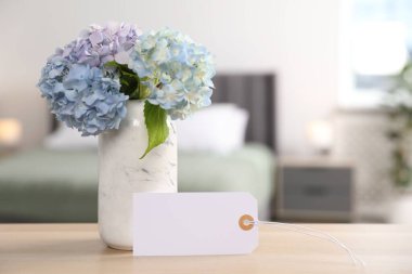 Boş kart ve ortanca çiçekleri otel odasındaki ahşap masada. Metin için boşluk